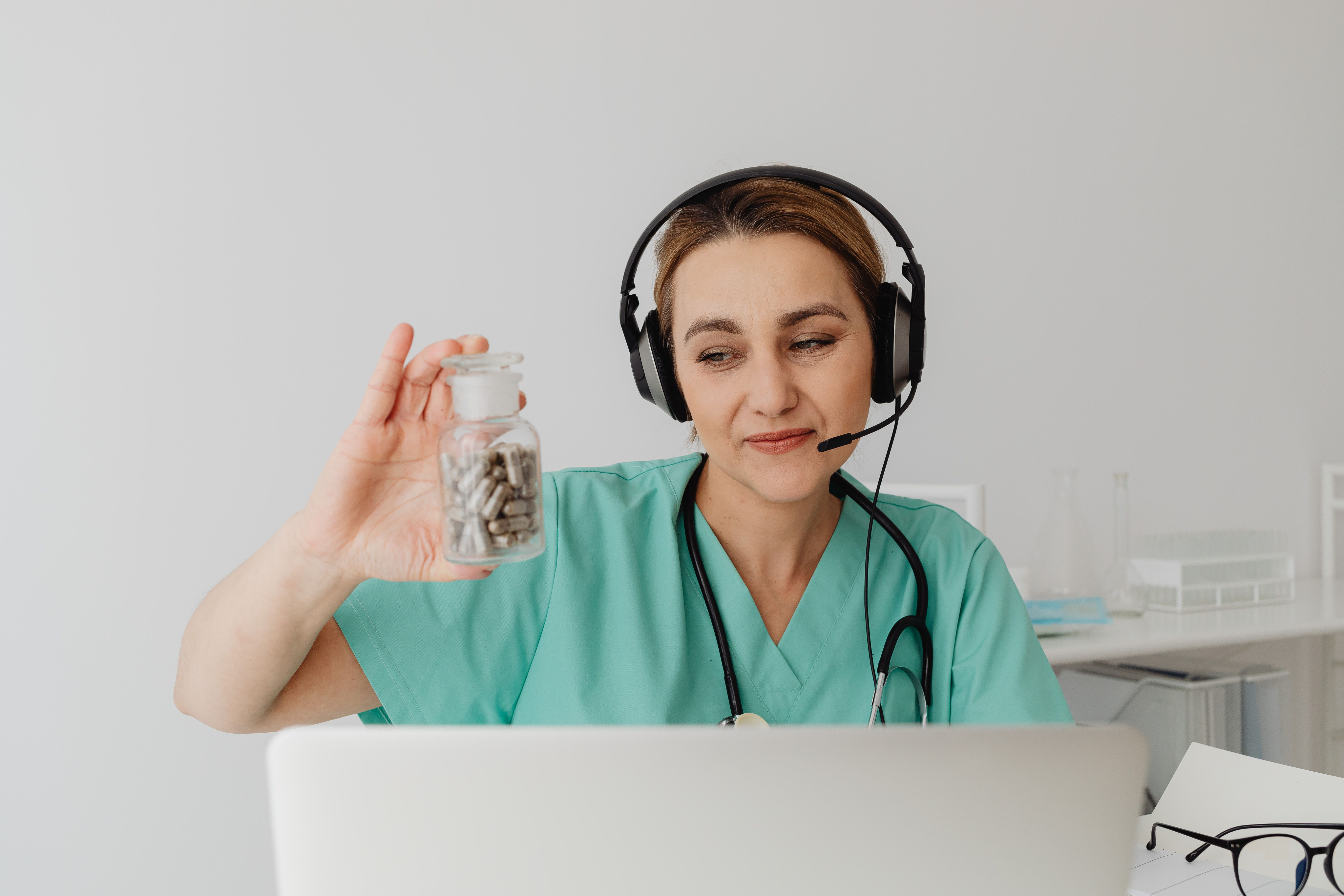 Healthcare provider on a virtual consultation holding a jar of capsules