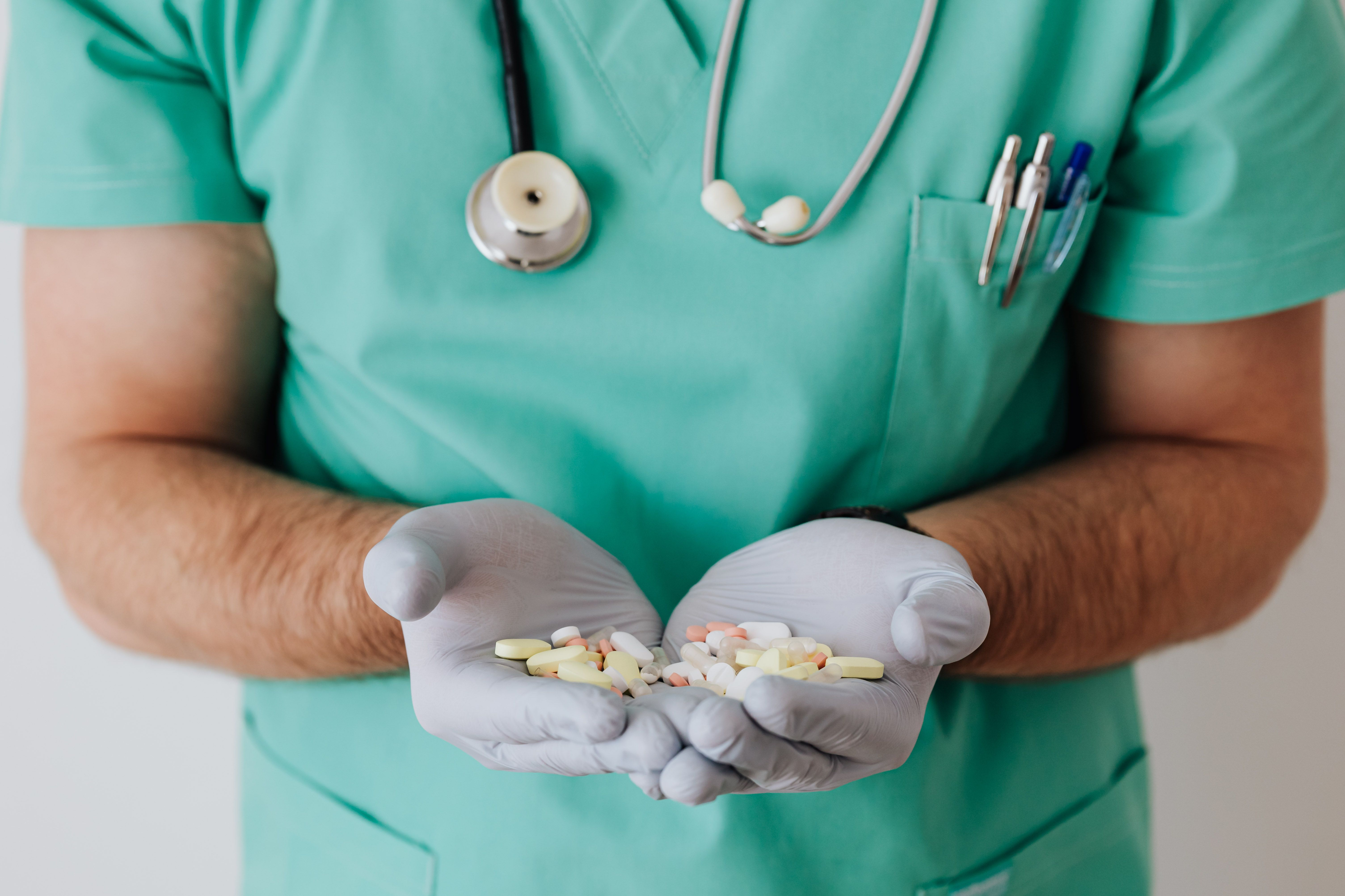 Healthcare professional in scrubs holding colorful tablets and capsules