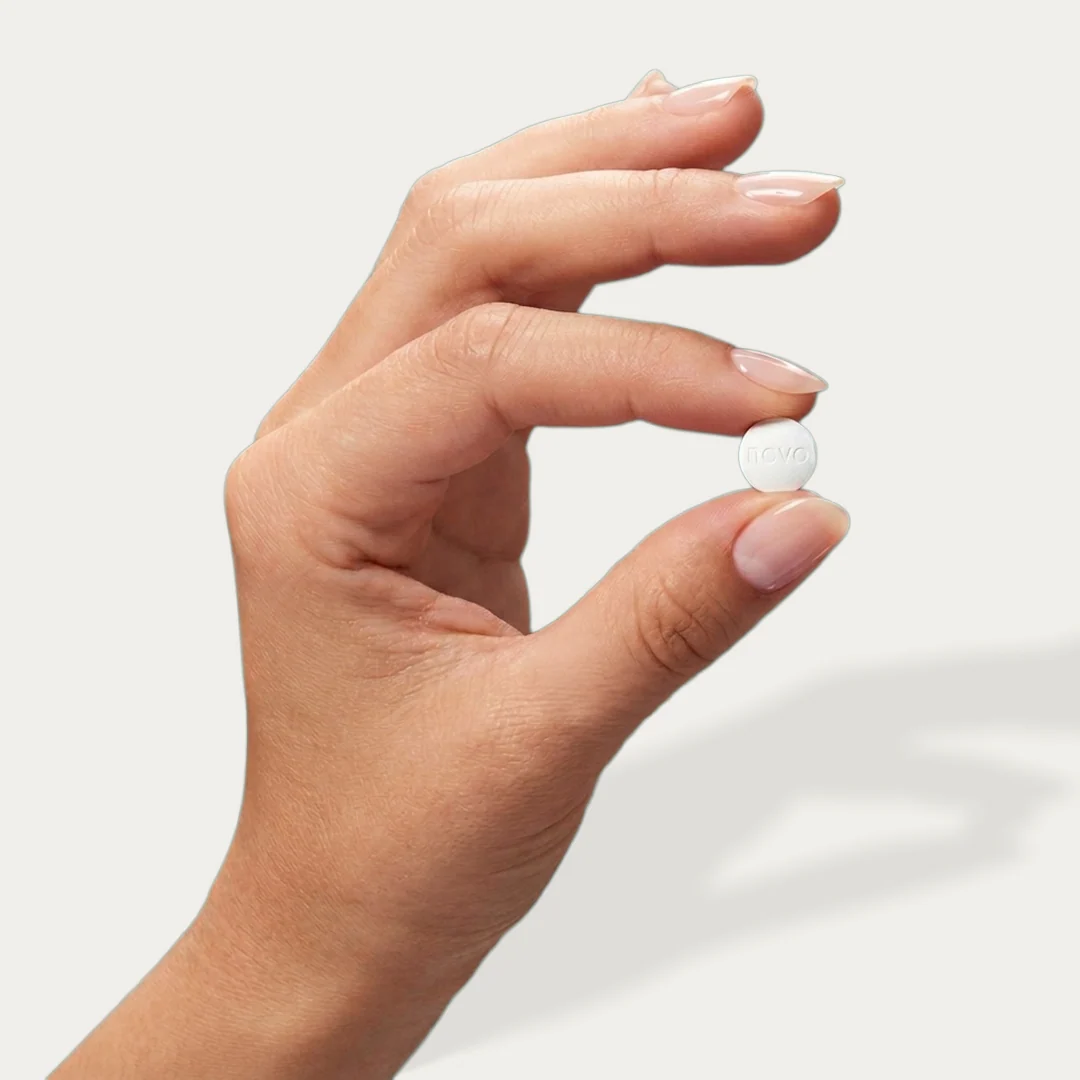 Hand holding a white medication tablet